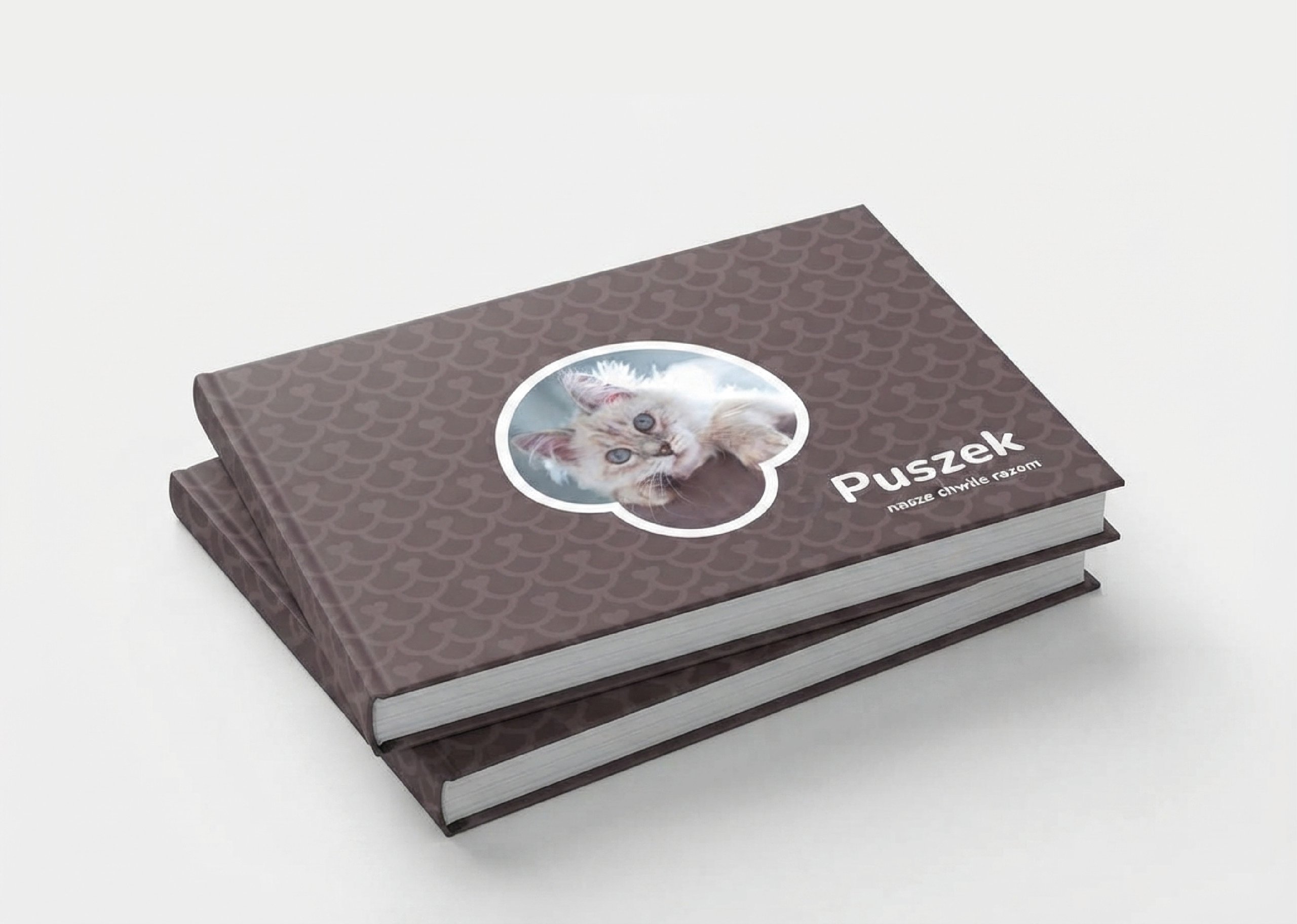 Three dark patterned books, one featuring a white kitten photo and the title “PUSZEK.”